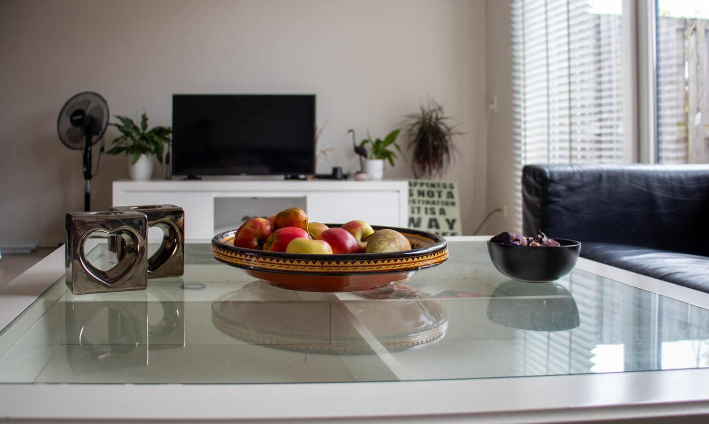 Glazen salontafel met een fruitschaal in een lichte woonkamer