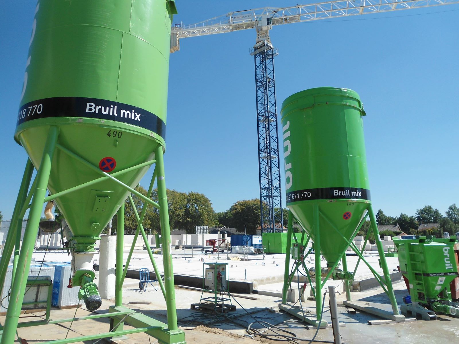 Groene silo’s van Bruil mix en een torenkraan op een bouwplaats