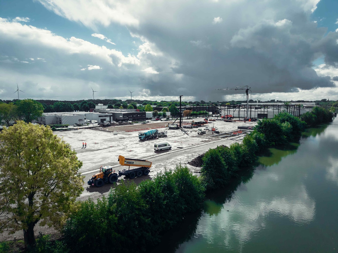 Luchtfoto van een bouwterrein met vrachtwagens naast een rivier
