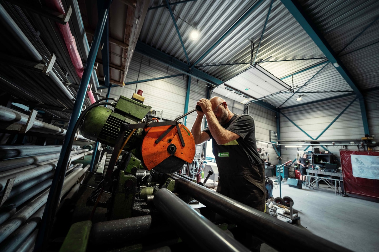 Medewerker bedient een zaagmachine tussen metalen buizen in een werkplaats