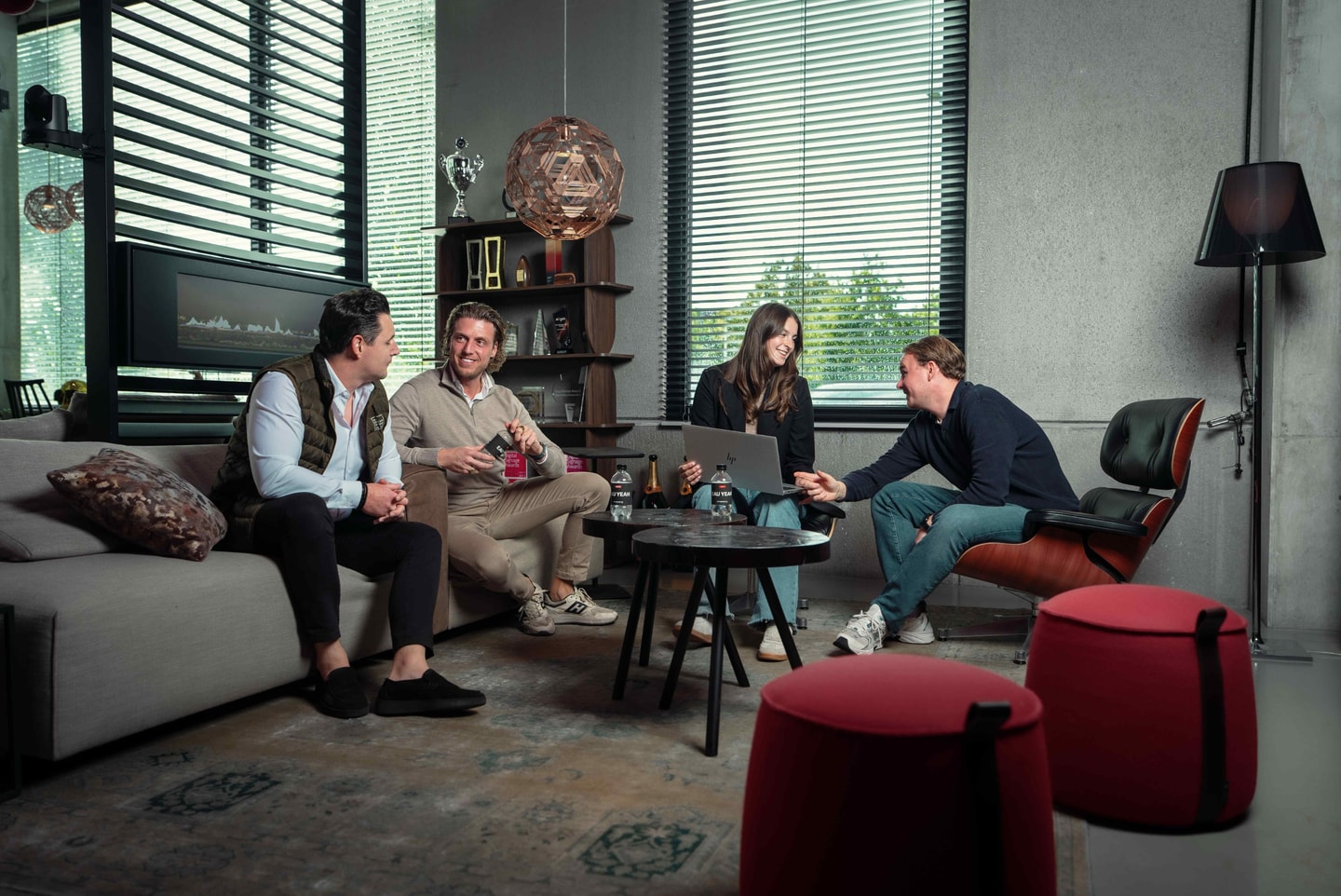 Vier mensen in gesprek in een loungehoek met banken en een leren fauteuil