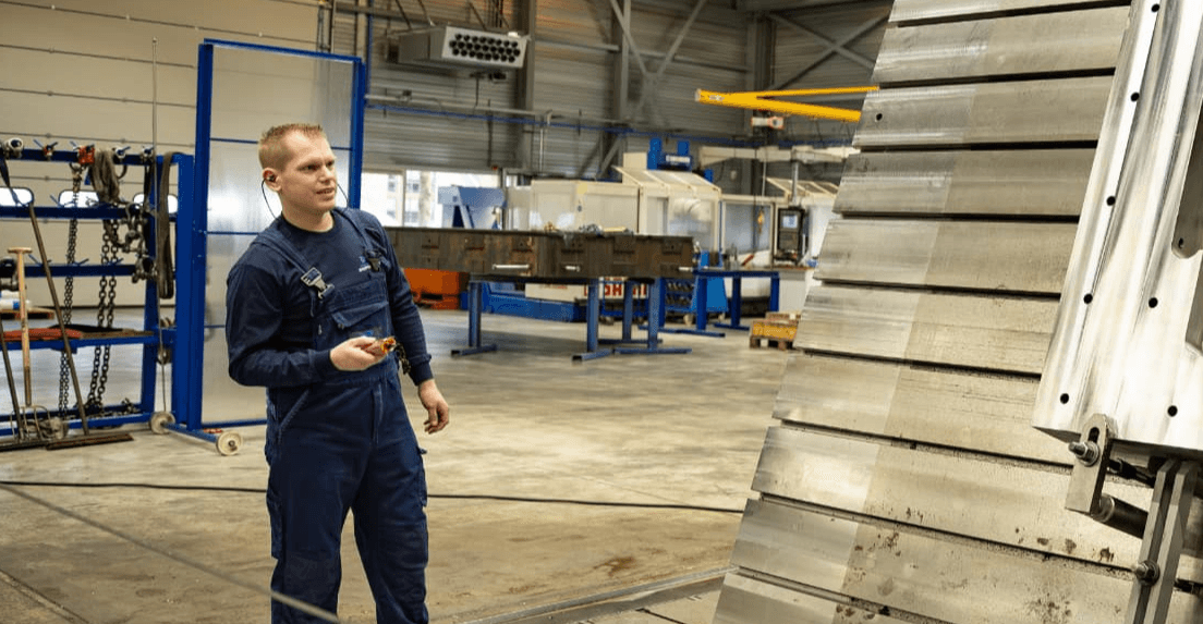 Monteur in blauwe overall in een hangar met werkbanken