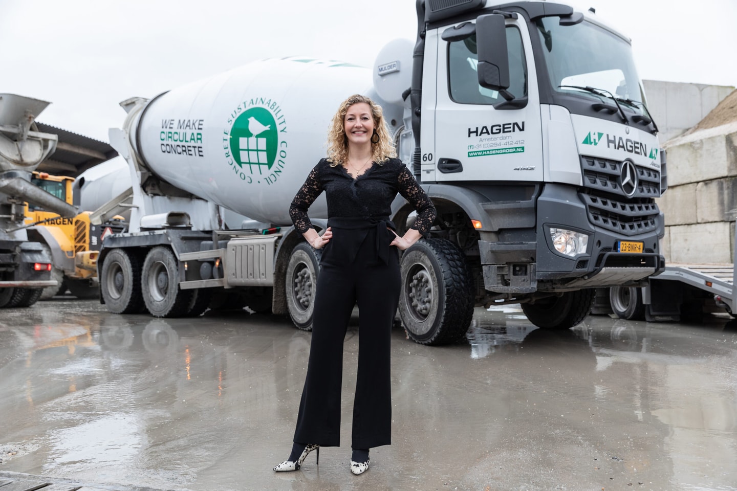Vrouw in zwarte jumpsuit voor een betonmixer van Hagen