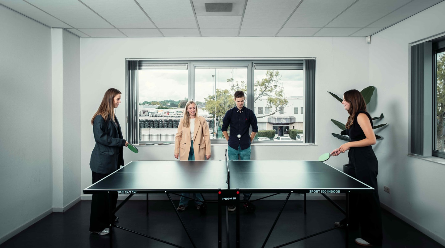 Vier collega’s spelen tafeltennis in een kantoorruimte