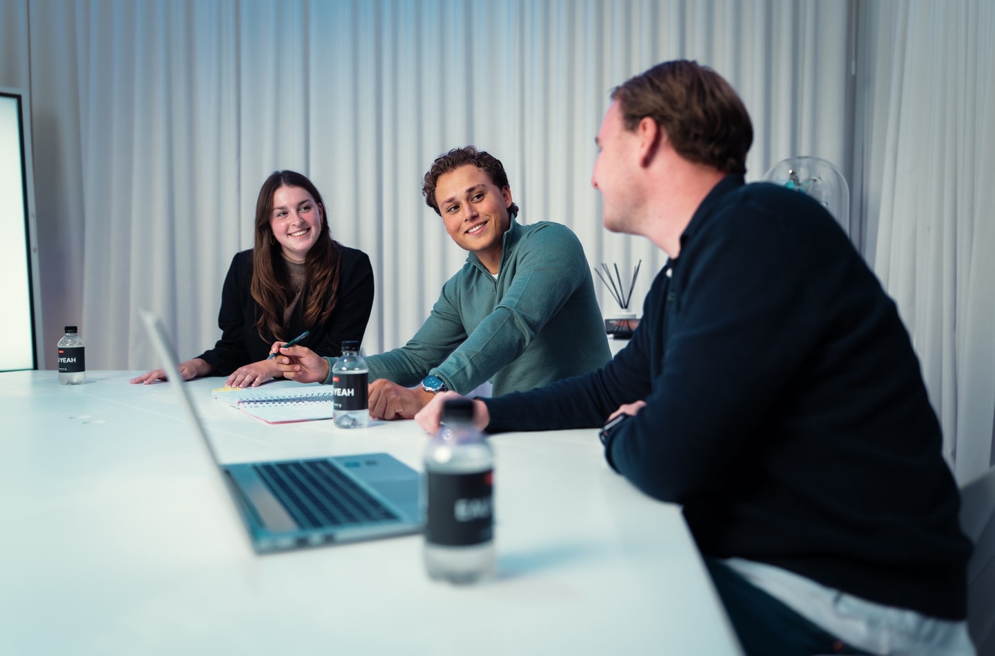 Drie collega’s van Diks Process Support in gesprek aan een vergadertafel met laptop