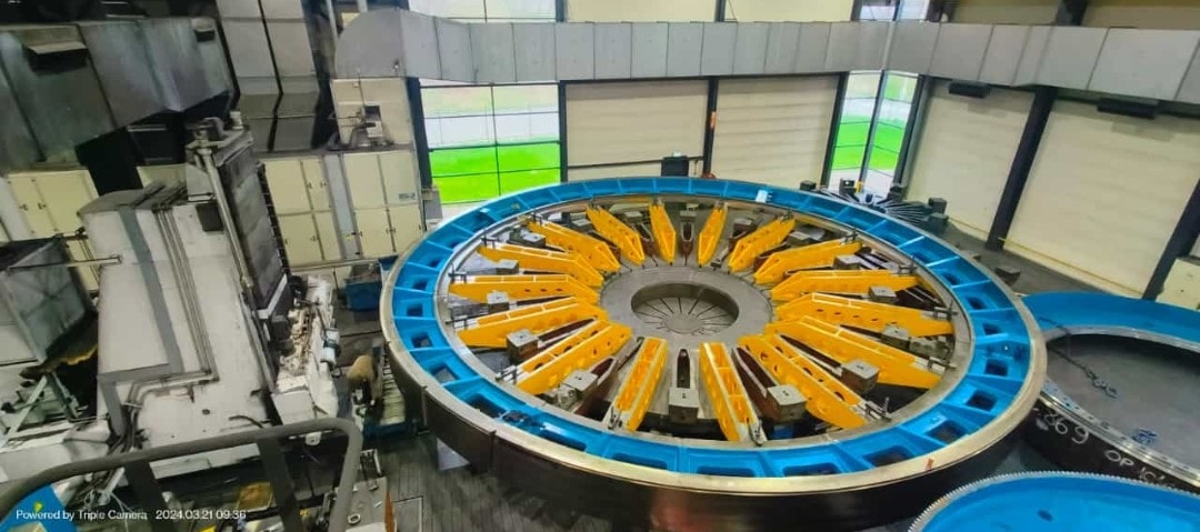 Rond carrouselapparaat met oranje onderdelen in een productieruimte