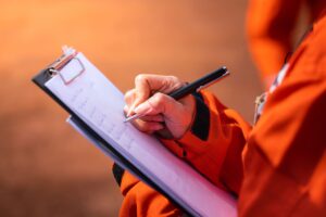 medewerker in een oranje pak schrijft op een checklist